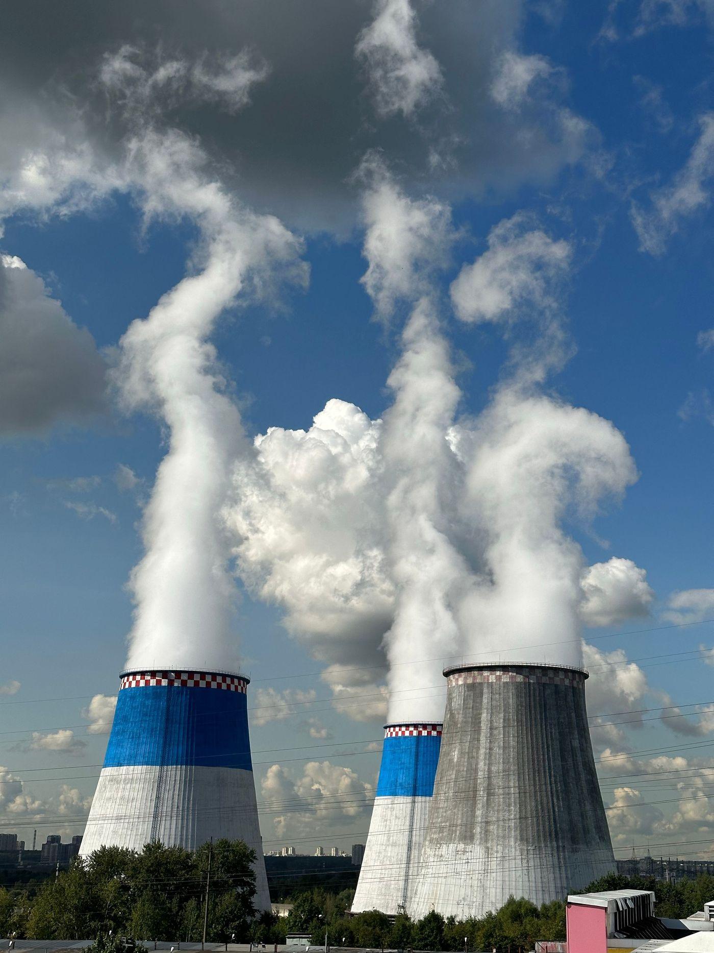 Three industrial cooling towers venting steam into a clear sky