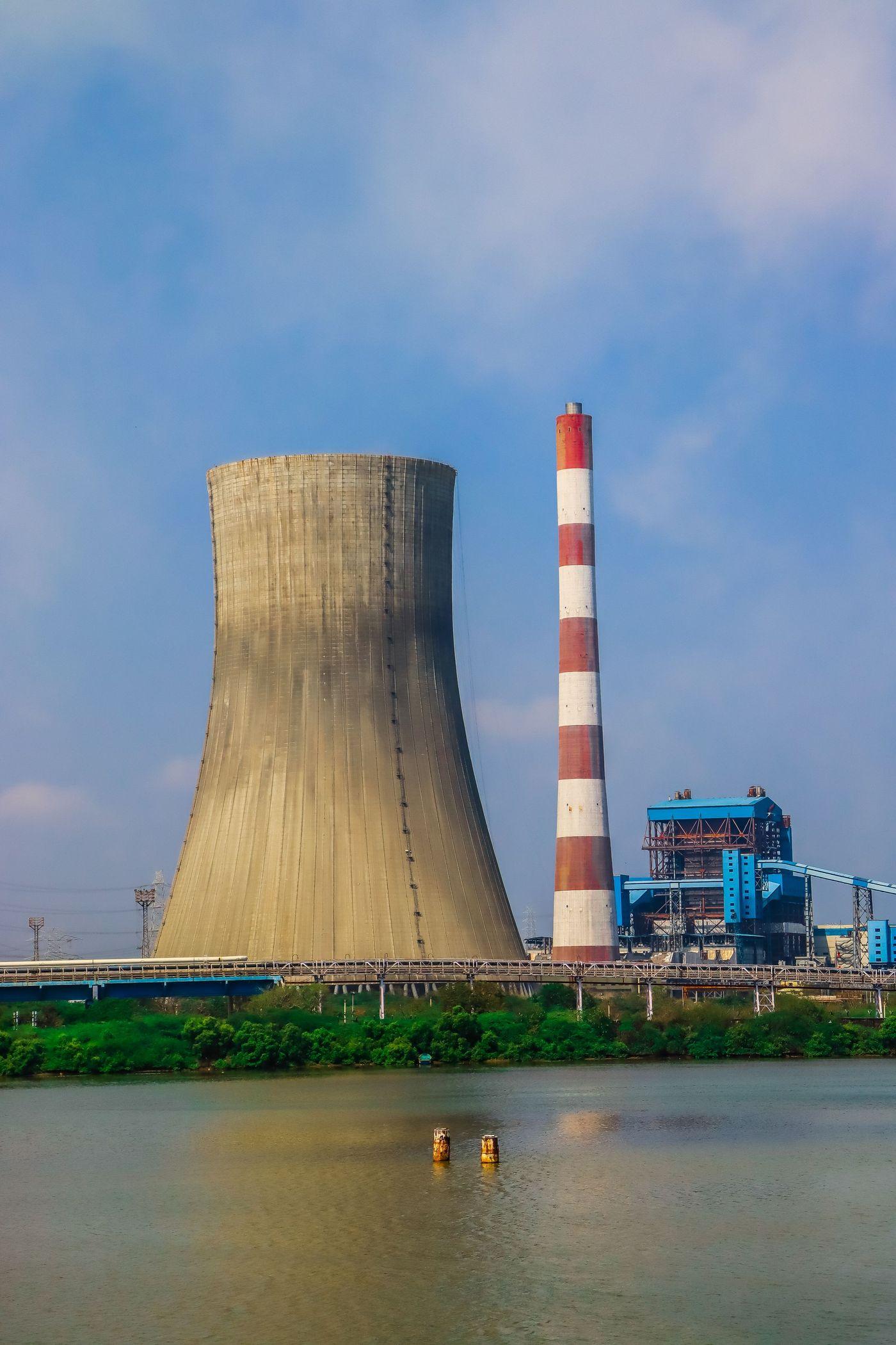 A cooling tower beside a river at an industrial power plant