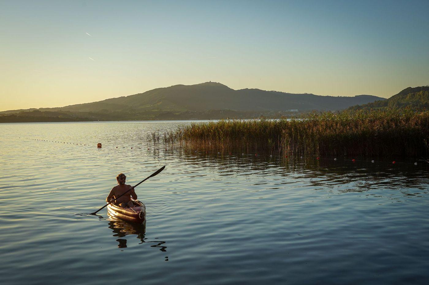 A kayaker crossing calm open lake water at the end of the day