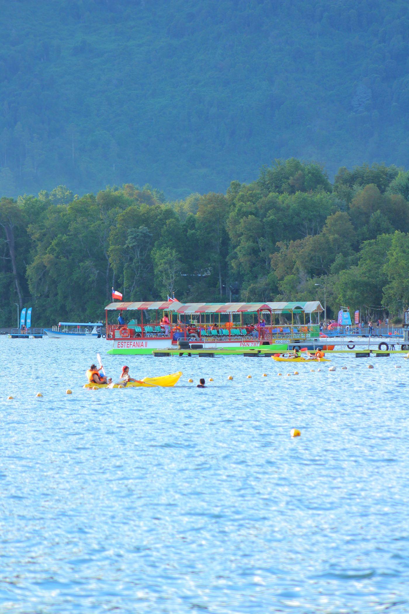 Canoes on open lake water below wooded hills