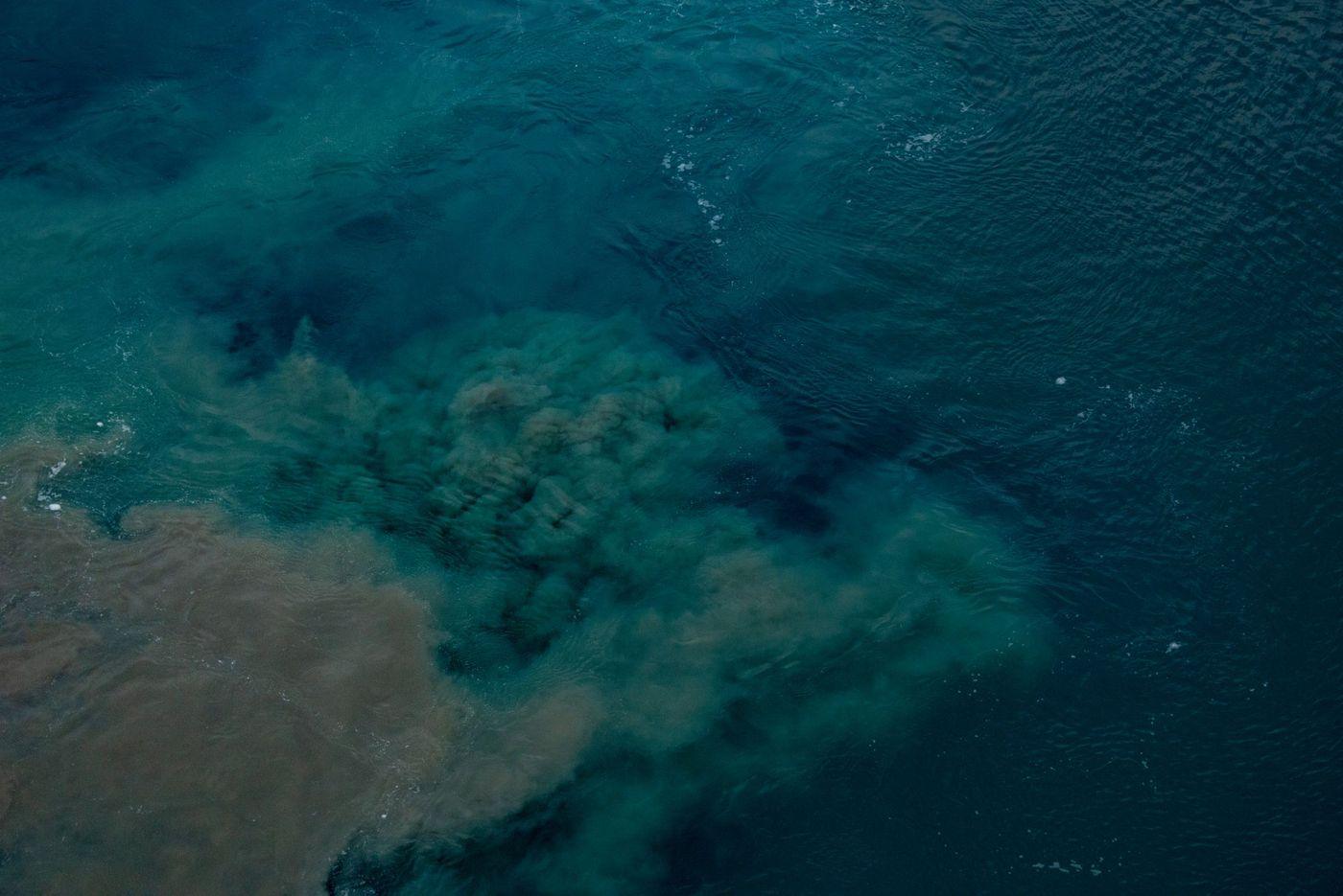 Aerial view of discoloured, turbid water spreading across a surface