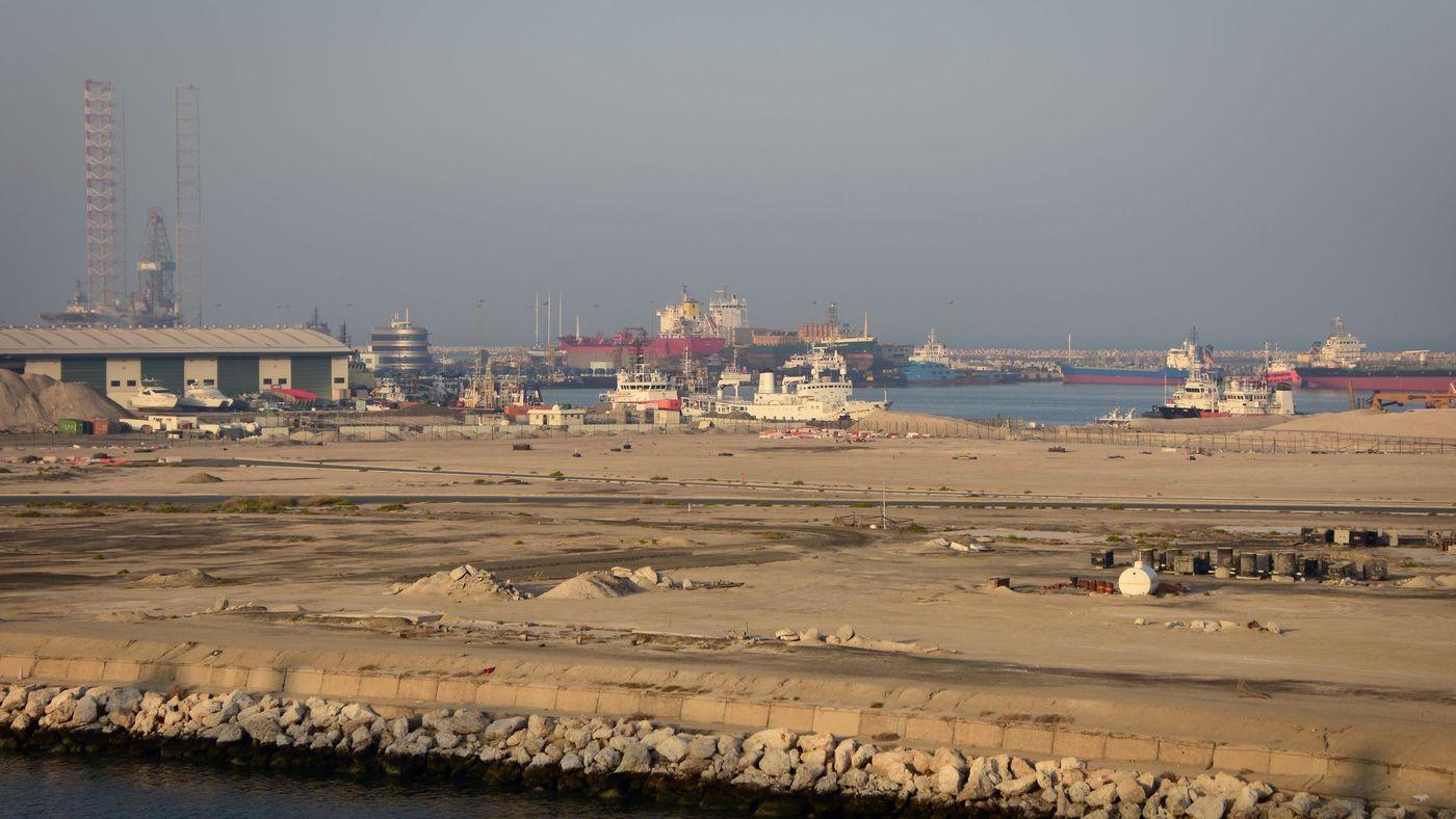 Tankers and support vessels moored along a working commercial waterfront at dusk