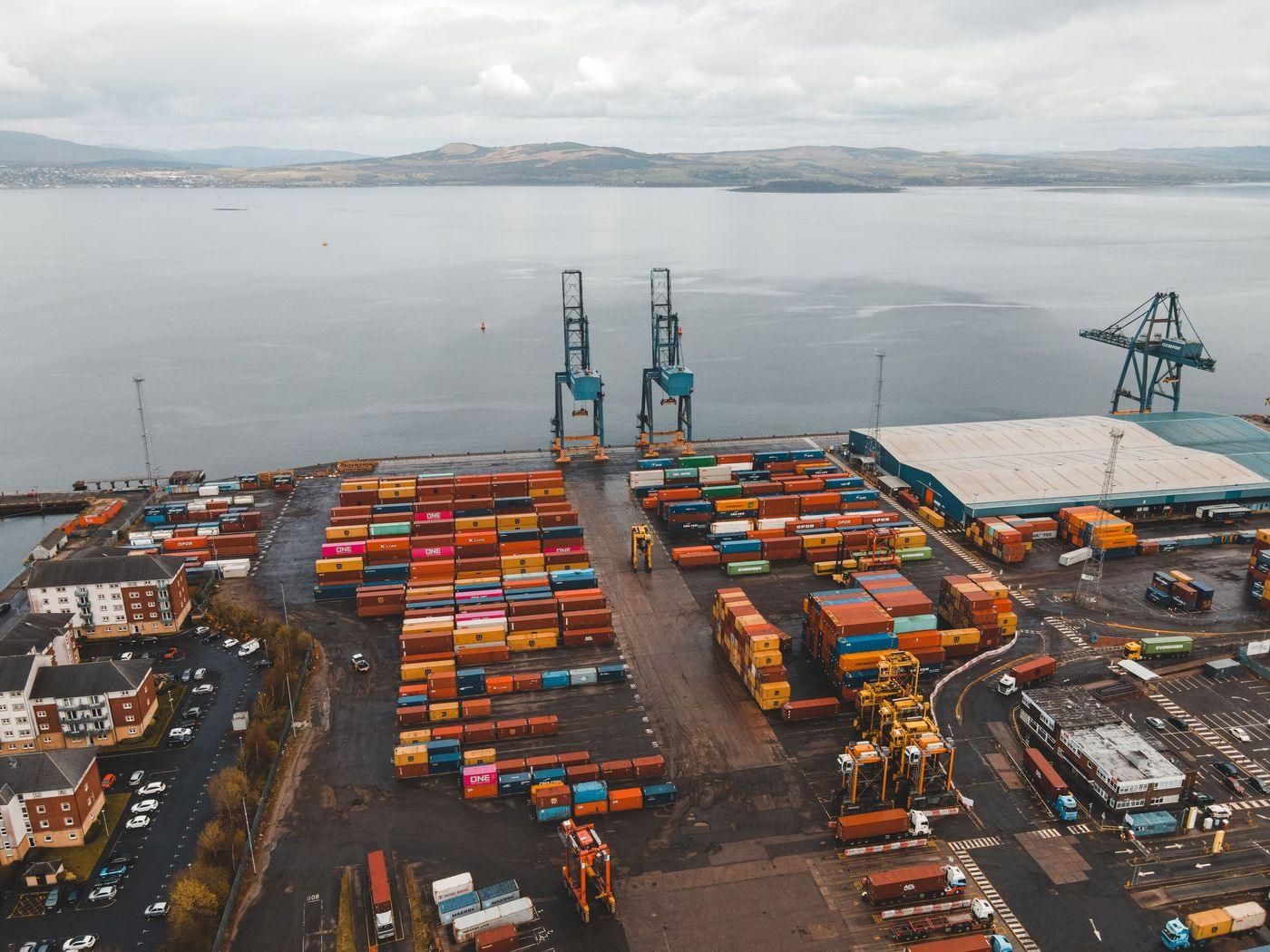 Rows of stacked cargo containers and gantry cranes at a working container terminal